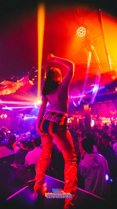 A performer under red and purple lights at 100% Reggaeton